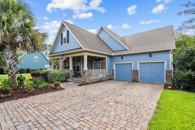 view of front of house with a front lawn, an attached garage, decorative driveway, brick siding, and a porch