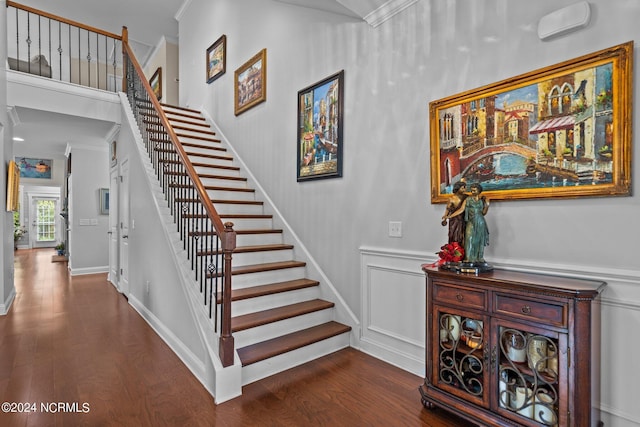 stairs featuring crown molding, wainscoting, and wood finished floors