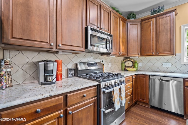 kitchen with light stone counters, decorative backsplash, appliances with stainless steel finishes, and dark wood-style floors