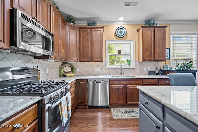 kitchen with visible vents, crown molding, a sink, light stone counters, and stainless steel appliances