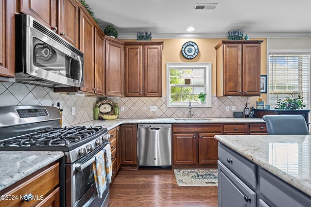 909 Tidalwalk Dr, Wilmington, NC 28409 - kitchen featuring stainless steel appliances, a sink, crown molding, light stone counters, and dark wood-type flooring