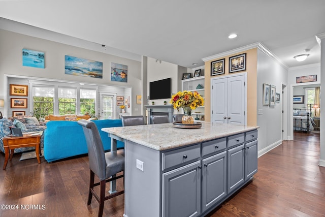 kitchen with gray cabinets, a kitchen island, crown molding, dark wood-style floors, and open floor plan
