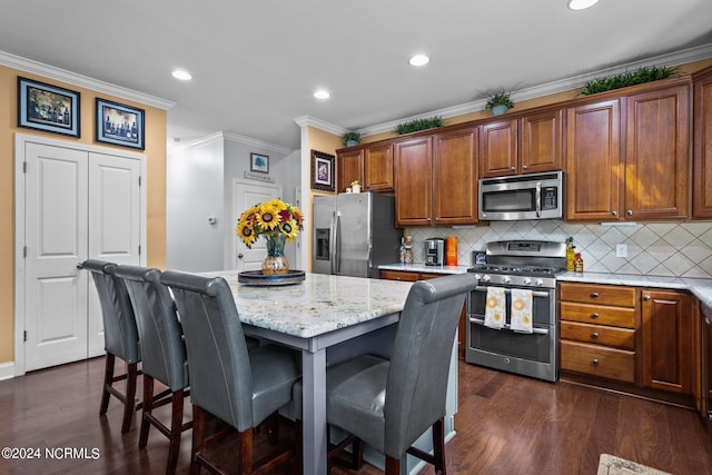 kitchen with crown molding, decorative backsplash, a kitchen island, light stone counters, and stainless steel appliances