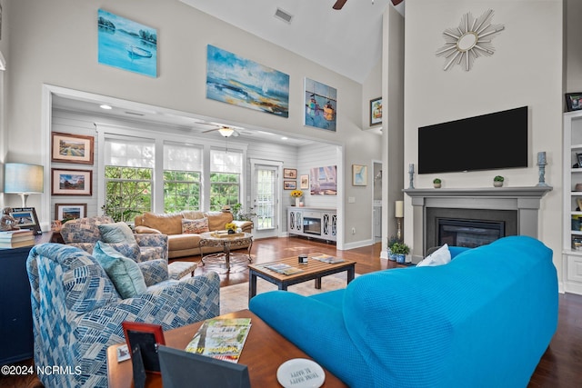 living area with a ceiling fan, visible vents, wood finished floors, high vaulted ceiling, and a glass covered fireplace