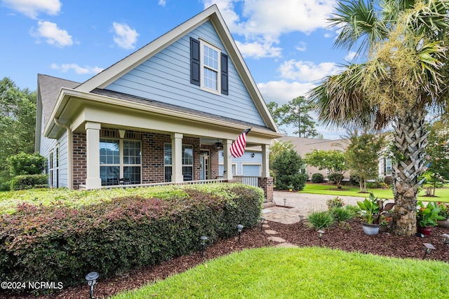 bungalow-style home featuring brick siding, a front lawn, and a porch