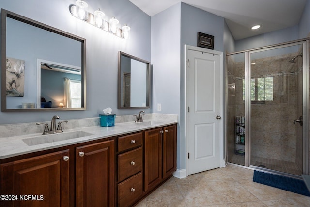 full bath featuring double vanity, a shower stall, and a sink