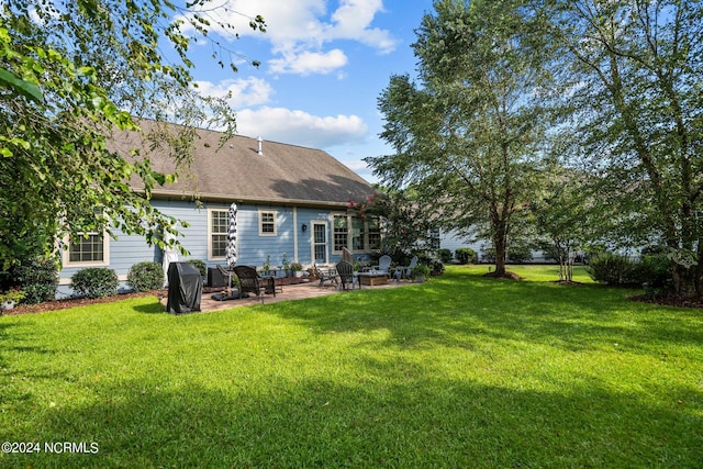 rear view of property featuring a shingled roof, a yard, and a patio area