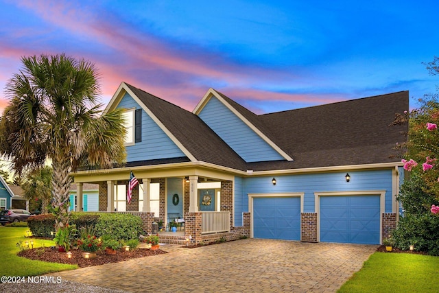 view of front of property with brick siding, decorative driveway, a garage, and covered porch