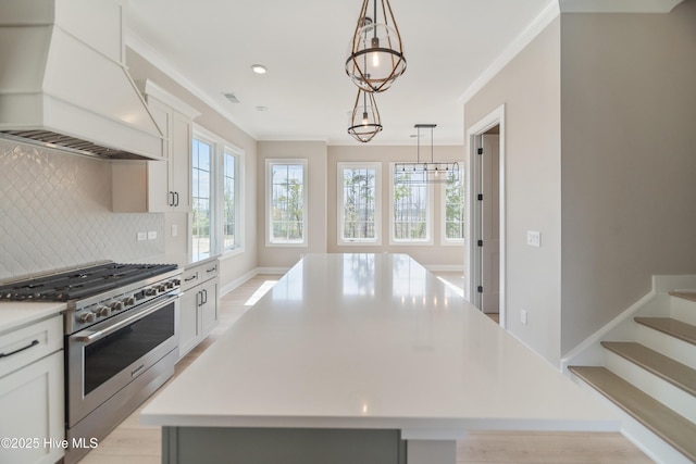 2652 Alvernia Dr, Castle Hayne, NC 28429 - kitchen with custom exhaust hood, gas range, backsplash, light countertops, and a kitchen island