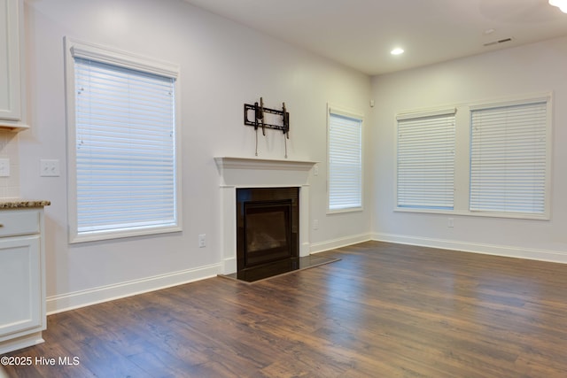 5225 National Garden Trl, Winnabow, NC 28479 - unfurnished living room with baseboards, dark wood finished floors, a glass covered fireplace, and visible vents