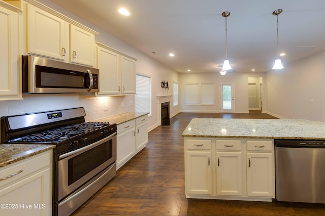 5225 National Garden Trl, Winnabow, NC 28479 - kitchen featuring backsplash, appliances with stainless steel finishes, hanging light fixtures, a fireplace, and dark wood-type flooring
