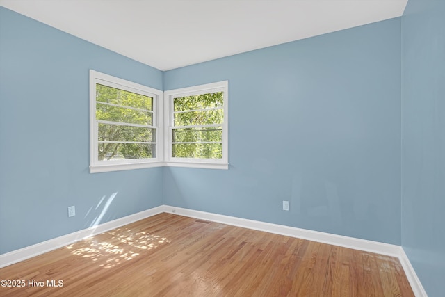 empty room with baseboards, visible vents, and light wood-type flooring