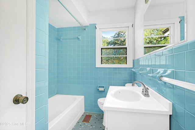 bathroom with vanity, toilet, tile walls, bathtub / shower combination, and tile patterned floors