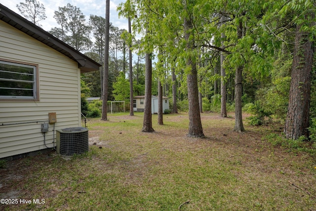 view of yard featuring central AC unit and an outdoor structure