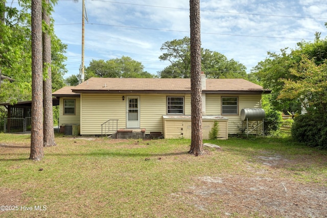 rear view of house with a lawn, heating fuel, and cooling unit