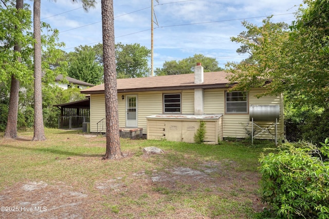 back of house featuring a yard and a chimney