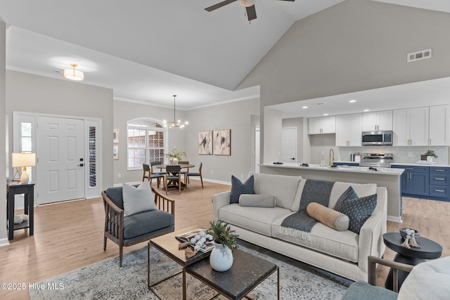 living room with light wood-style floors, ceiling fan with notable chandelier, and visible vents