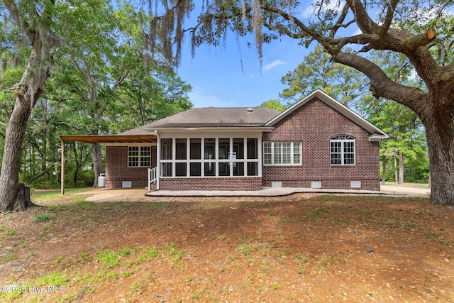 rear view of house with roof with shingles, a sunroom, brick siding, and crawl space