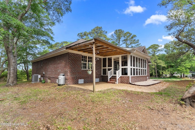 rear view of property with crawl space, a patio area, a sunroom, brick siding, and cooling unit