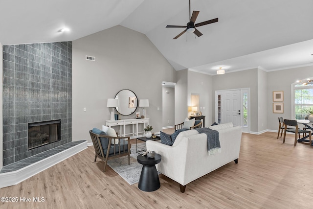 living area with baseboards, a fireplace, ceiling fan with notable chandelier, and light wood-style flooring