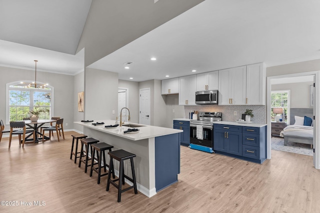 kitchen with a breakfast bar area, light wood-type flooring, blue cabinets, a sink, and appliances with stainless steel finishes