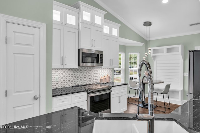 kitchen featuring visible vents, crown molding, lofted ceiling, tasteful backsplash, and stainless steel appliances