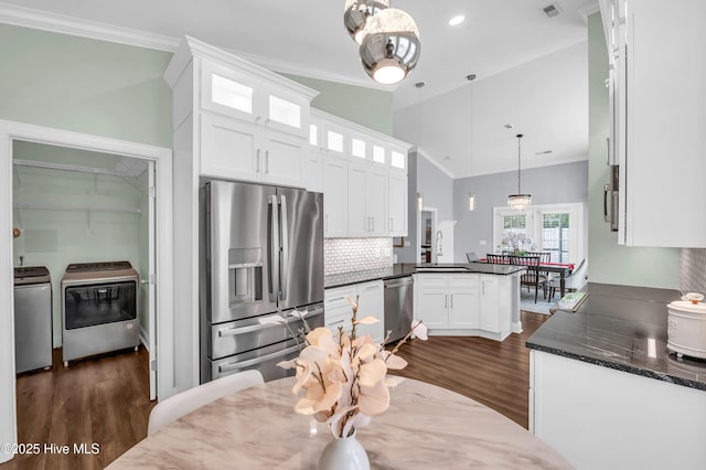 kitchen with washer and dryer, a peninsula, appliances with stainless steel finishes, and dark wood finished floors