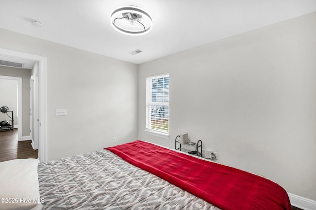 bedroom featuring visible vents, baseboards, and wood finished floors