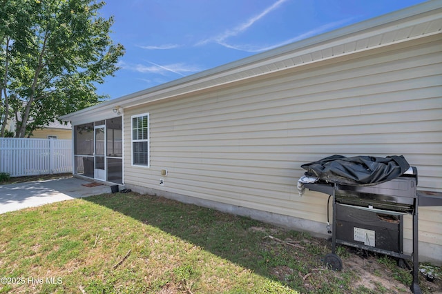 rear view of property featuring a yard, fence, and a sunroom