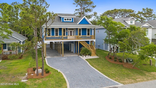 226 NE 64th St, Oak Island, NC 28465 - coastal home featuring a carport, gravel driveway, covered porch, and a front lawn