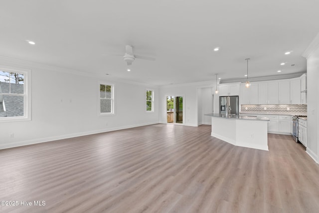 226 NE 64th St, Oak Island, NC 28465 - unfurnished living room with crown molding, plenty of natural light, recessed lighting, light wood finished floors, and a ceiling fan