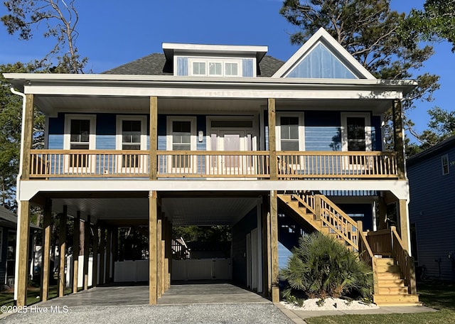 coastal home with board and batten siding, a porch, a carport, stairway, and a shingled roof