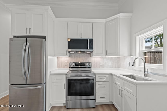226 NE 64th St, Oak Island, NC 28465 - kitchen featuring stainless steel appliances, a sink, white cabinetry, light countertops, and light wood-style flooring