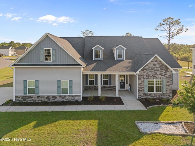 exterior space with board and batten siding, a front yard, a porch, and stone siding