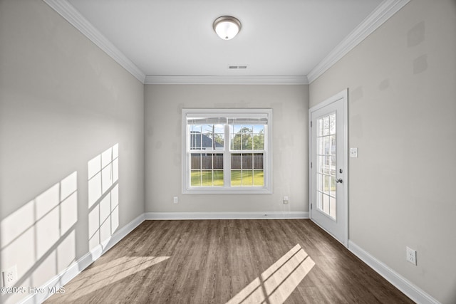 interior space featuring visible vents, ornamental molding, baseboards, and wood finished floors