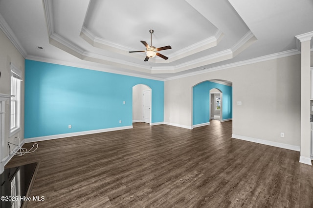 empty room with baseboards, dark wood-style floors, a raised ceiling, arched walkways, and a ceiling fan