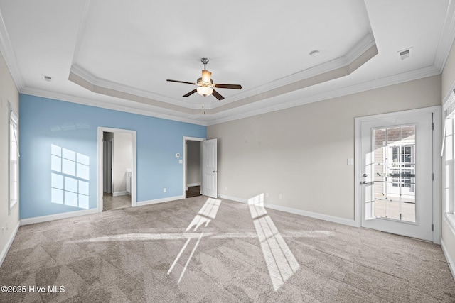unfurnished bedroom featuring crown molding, light colored carpet, baseboards, a tray ceiling, and visible vents