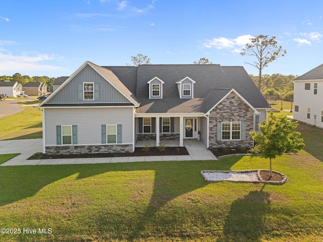 back of house featuring covered porch, board and batten siding, a yard, and stone siding