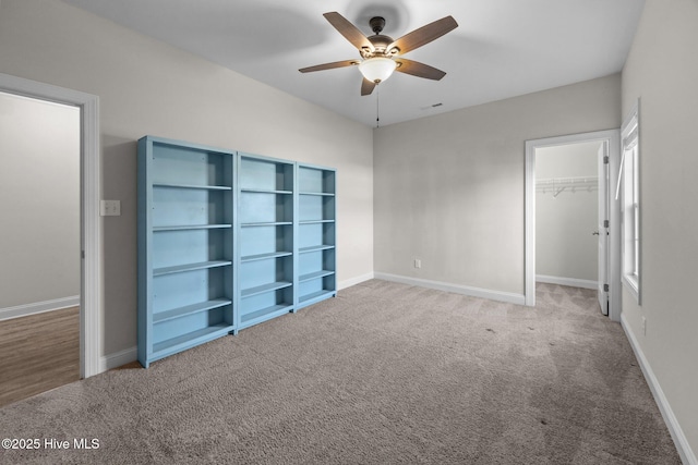 unfurnished bedroom with carpet floors, a ceiling fan, baseboards, a spacious closet, and a closet