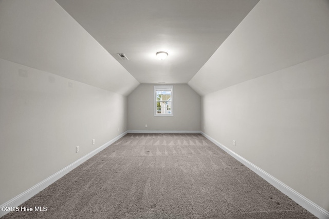 bonus room featuring baseboards, vaulted ceiling, light carpet, and visible vents