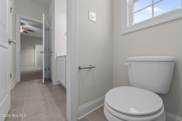 bathroom with toilet, a ceiling fan, baseboards, and tile patterned flooring