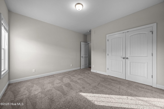 unfurnished bedroom with carpet floors, baseboards, and a closet