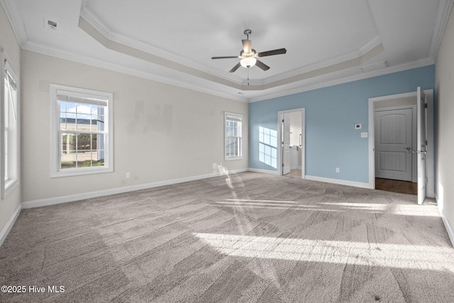 unfurnished bedroom with ornamental molding, baseboards, a tray ceiling, carpet, and ensuite bath