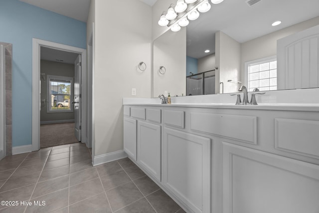 bathroom featuring visible vents, baseboards, tile patterned floors, a shower stall, and a sink