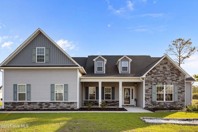 craftsman-style home with board and batten siding, a front yard, covered porch, and stone siding
