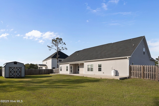 back of house featuring a lawn, a fenced backyard, a patio area, and a shed