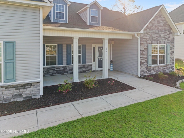 view of front of property with a porch, roof with shingles, and stone siding