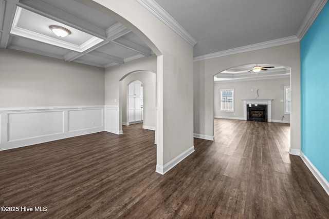 interior space with crown molding, ceiling fan, a fireplace, and dark wood-style flooring