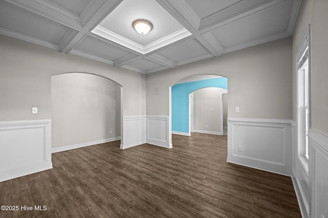 spare room featuring arched walkways, dark wood finished floors, beam ceiling, and coffered ceiling