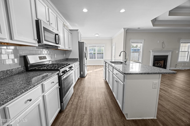 kitchen with a sink, ornamental molding, stainless steel appliances, and dark wood-style floors